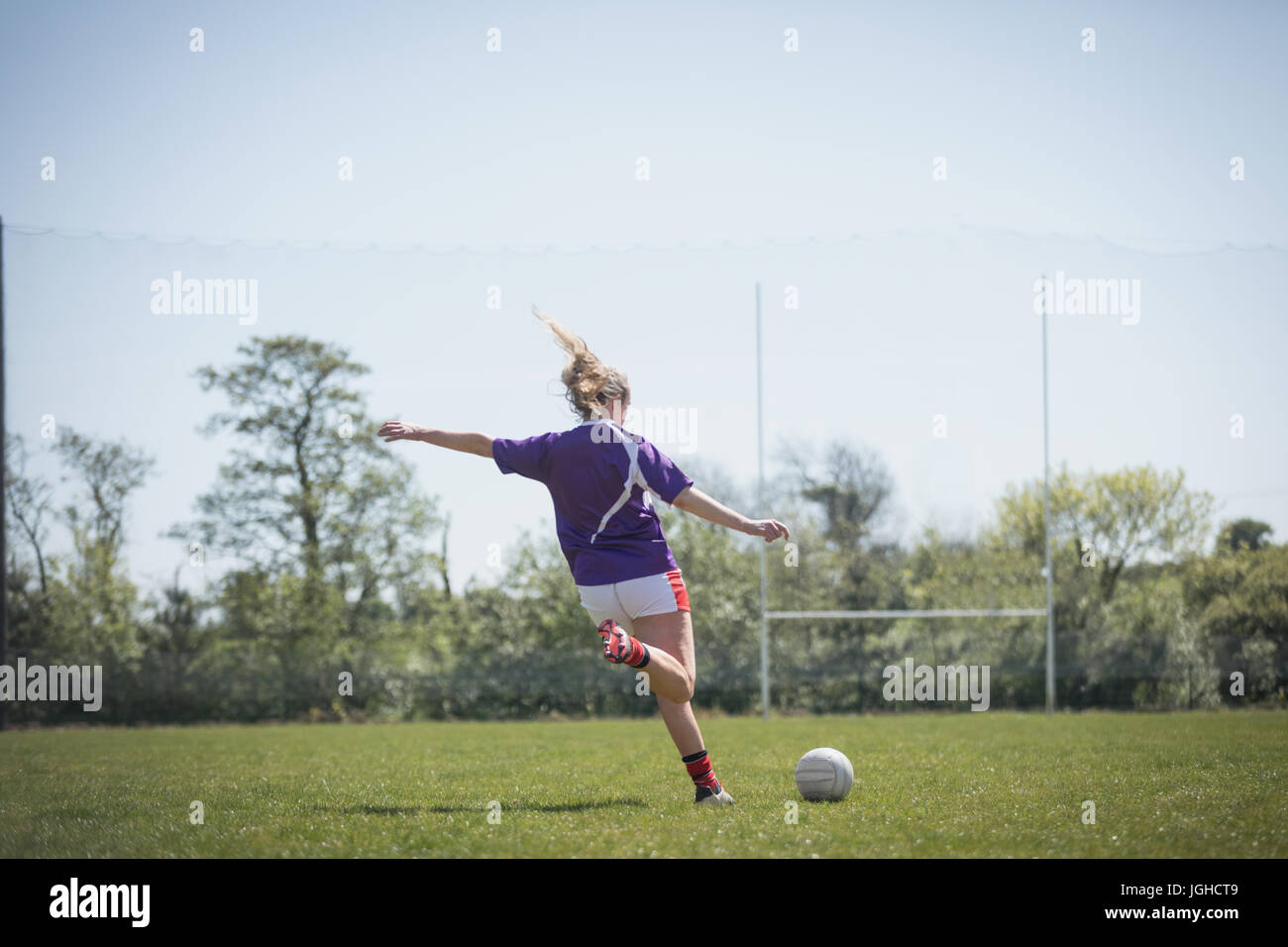 Rückansicht des jungen Frau spielen Fußball auf Feld gegen Himmel Stockfoto