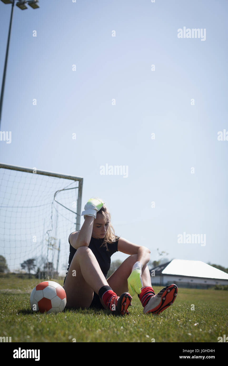 Gesamte Länge der müde Spielerin ruht auf Fußballplatz Stockfoto