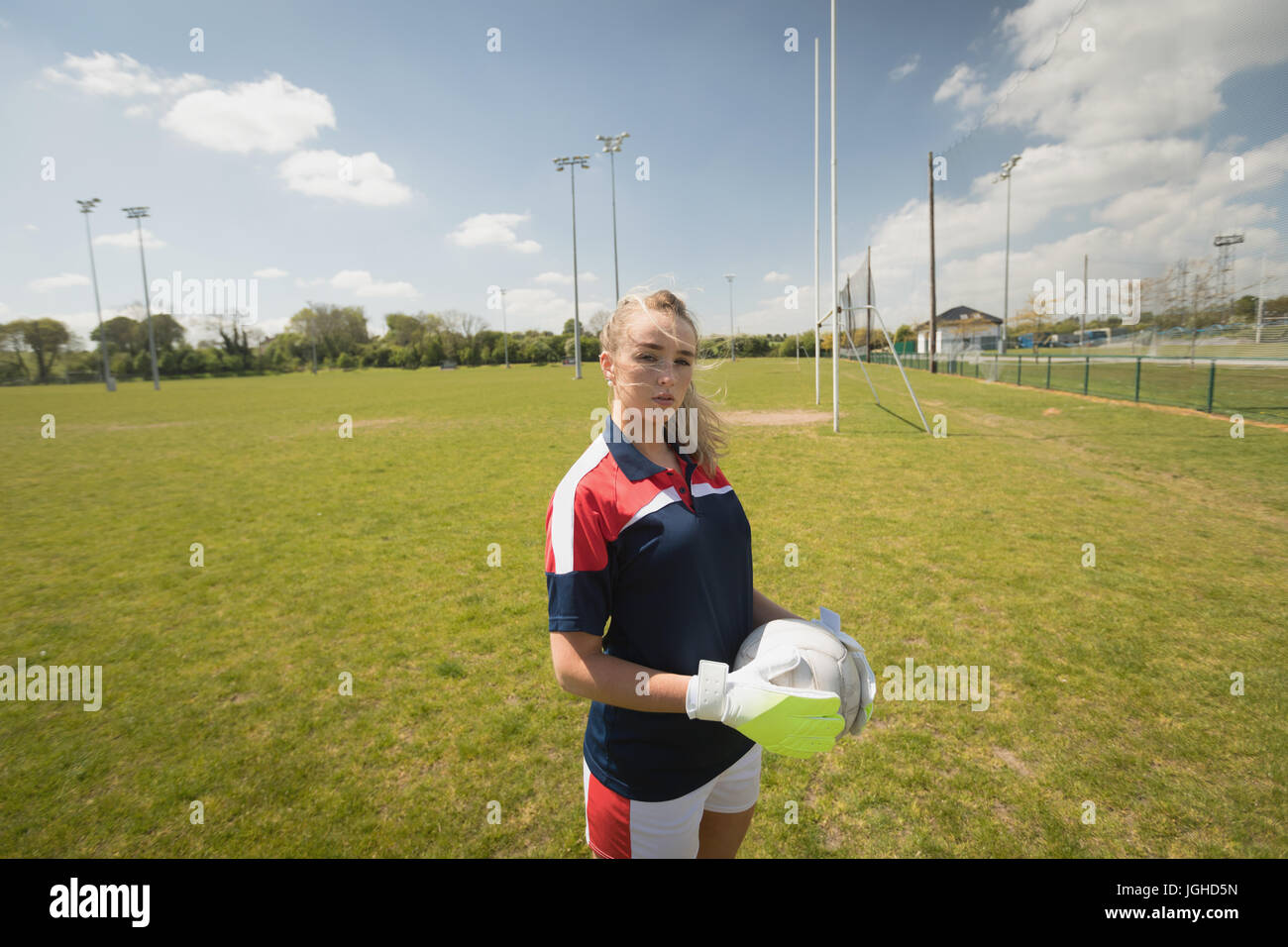 Junge weibliche Torwart Feld gegen Himmel Fußball beim stehen festhalten Stockfoto