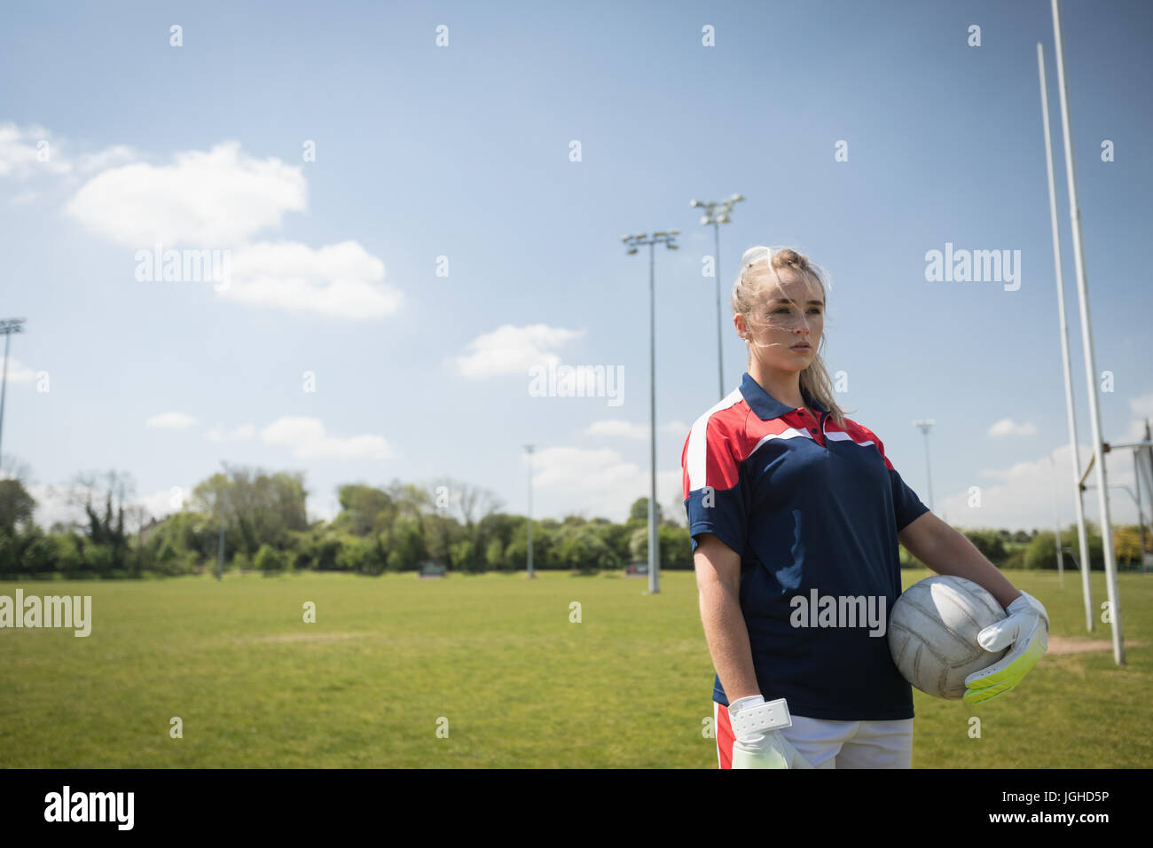 Junge weibliche Torwart mit Fußball Ball wegsehen auf Feld Stockfoto