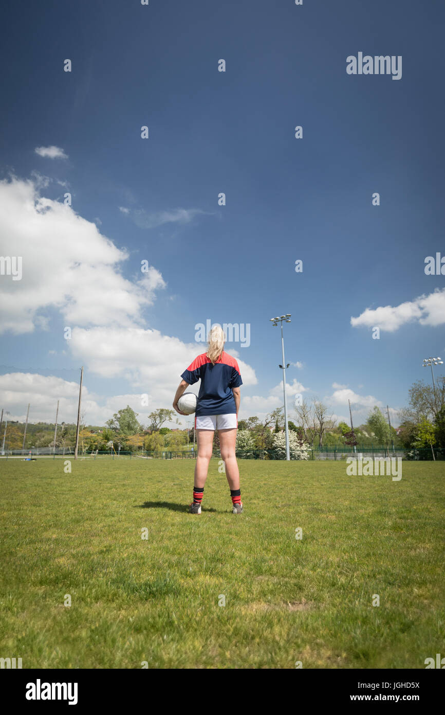 Rückansicht des weiblichen Spieler, Fußball auf Spielfeld gegen Himmel Stockfoto