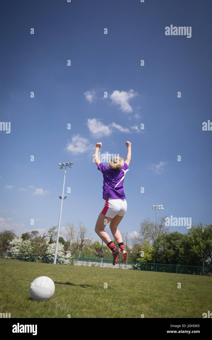 Rückseite Blick voller Länge des weiblichen Fußballspieler springen auf auffangene gegen Himmel Stockfoto