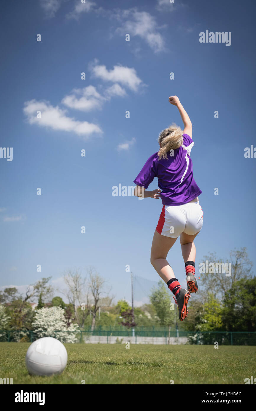 Rückseite Blick voller Länge des weiblichen Fußballspieler springen auf auffangene gegen Himmel Stockfoto