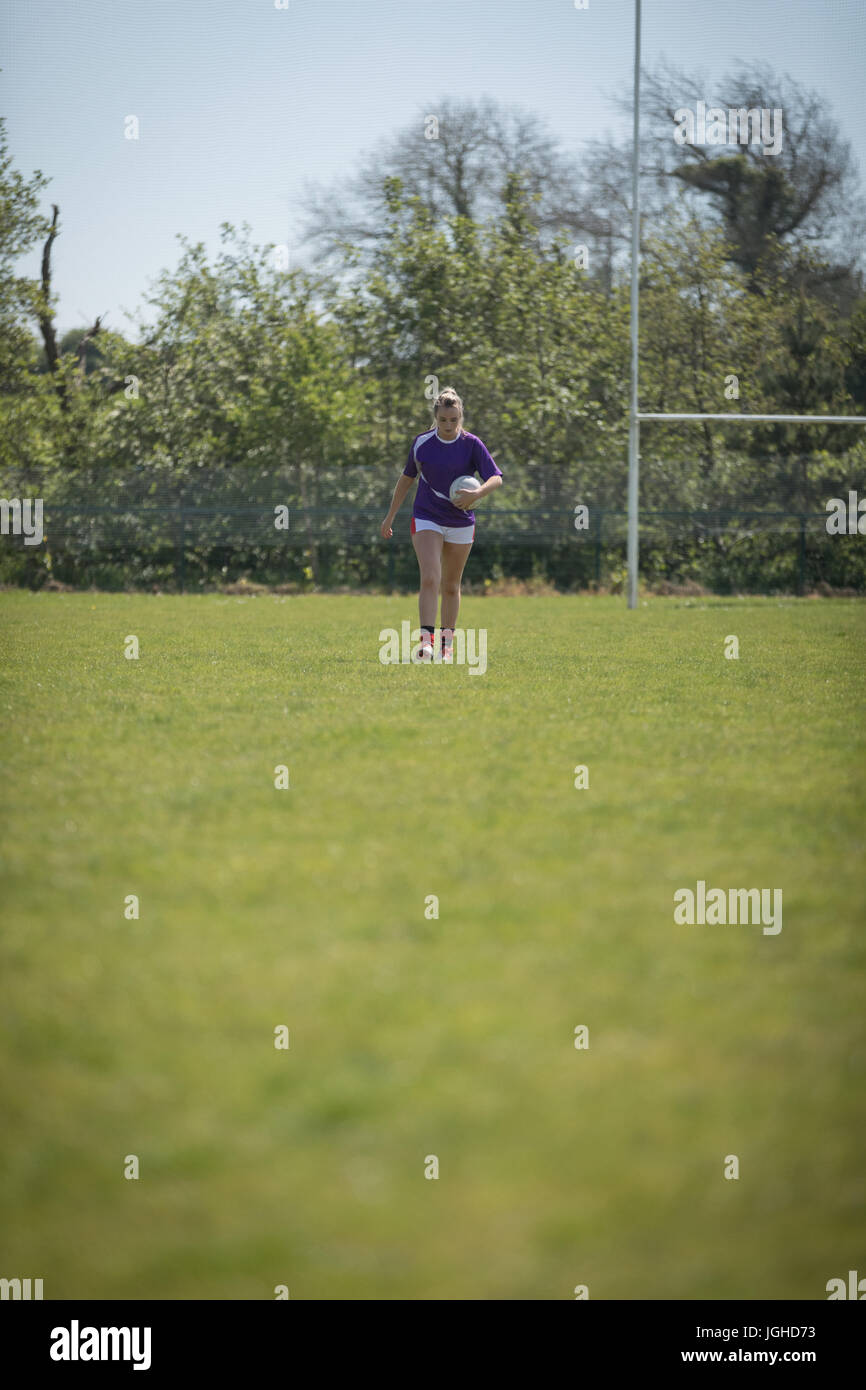 Gesamte Länge der Spielerin zu Fuß mit Fußball auf Feld Stockfoto