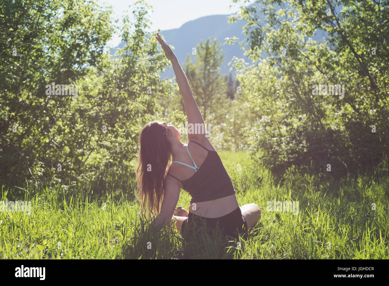 Rückansicht des Frau Yoga in einem grünen Wald an einem sonnigen Tag machen Stockfoto