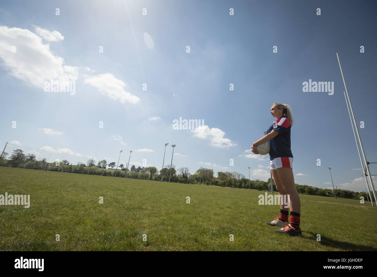 Volle Länge des Fußball-Spieler mit Ball stehend auf auffangene gegen Himmel Stockfoto