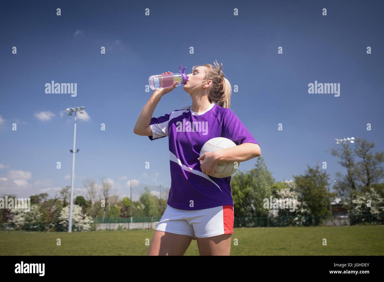 Durstig Fußballspieler mit Ball Trinkwasser auf Feld gegen Himmel Stockfoto