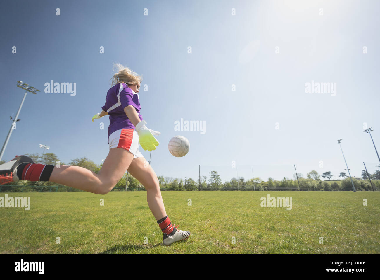 Gesamte Länge der Frau spielen Fußball auf Feld gegen Himmel an sonnigen Tag Stockfoto