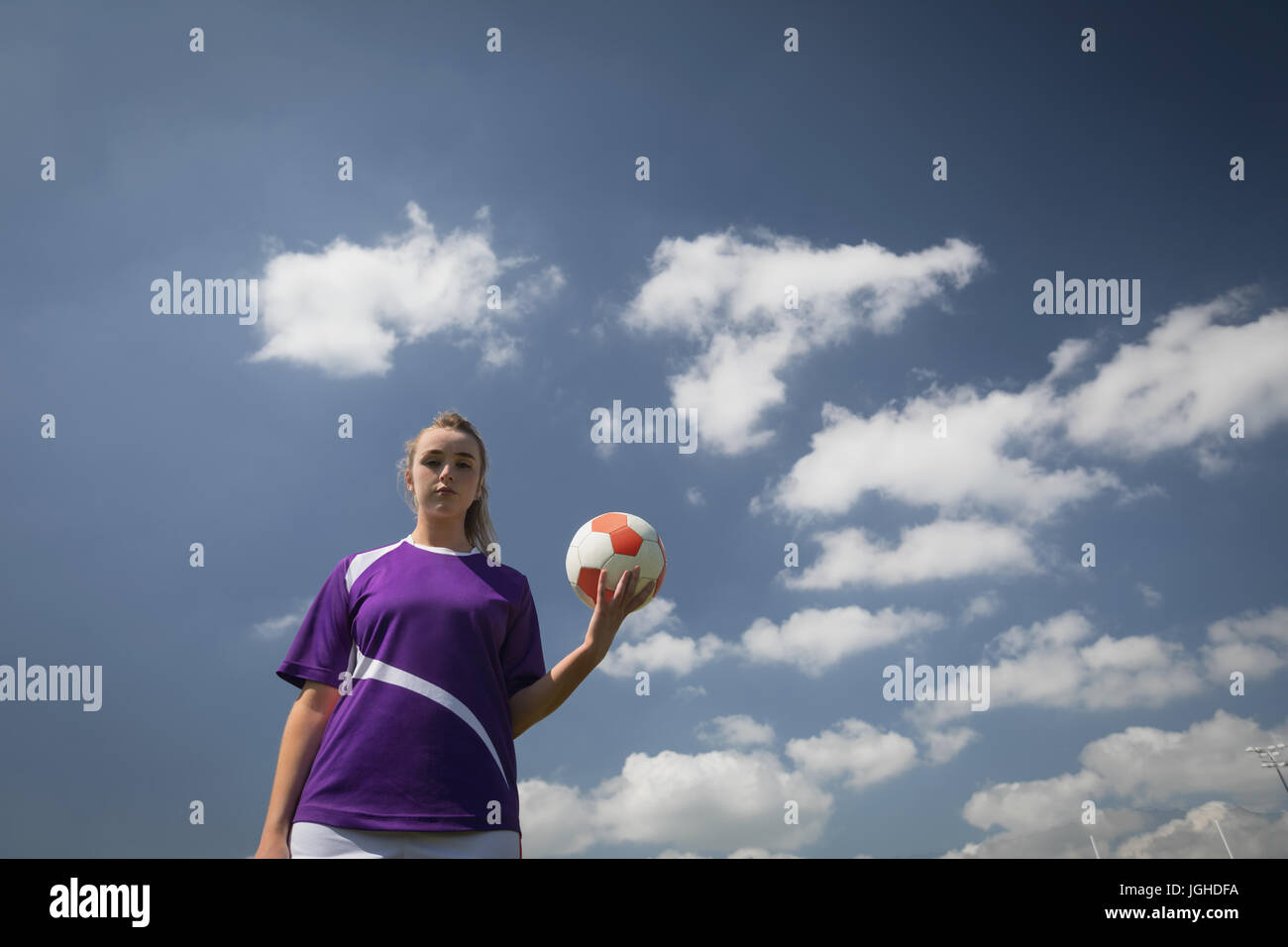 Niedrigen Winkel Blick der jungen Frau, die mit Fußball gegen bewölktem Himmel Stockfoto