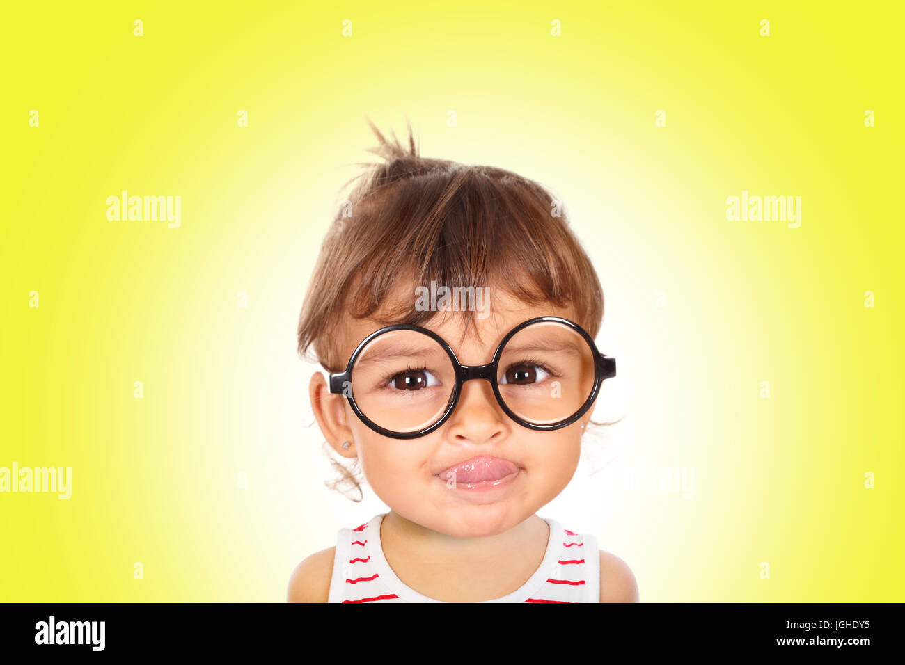 Porträt von lächelnden kleinen Mädchen mit schwarzen Brille Blick in die Kamera. Gelber Hintergrund Stockfoto