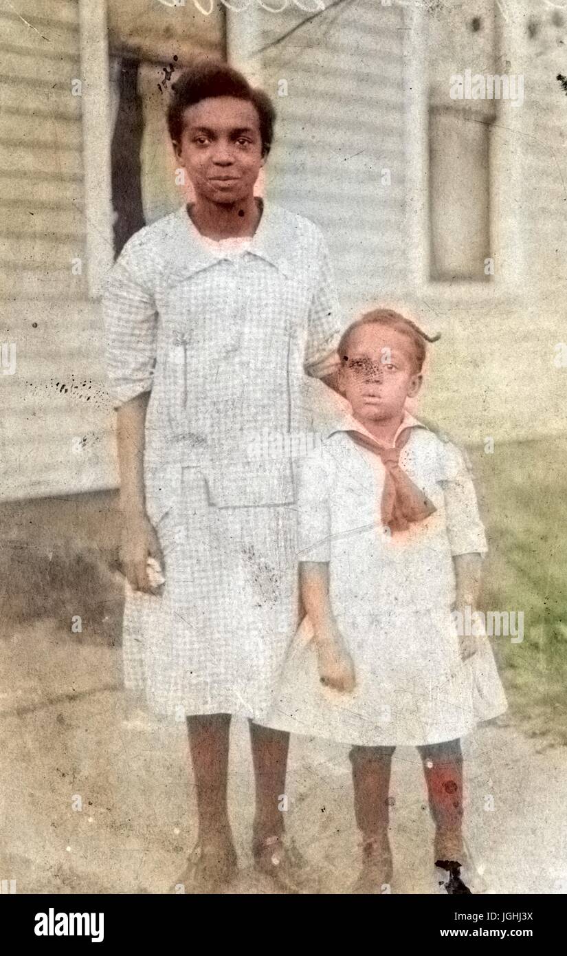 Porträt von zwei afroamerikanische Geschwister, sind beide jungen Mädchen tragen helle Outfits, das ältere Mädchen hat ihre Hand auf die jüngeren Mädchen auf die Schulter, 1920. Hinweis: Bild wurde digital eingefärbt wurde mit einem modernen Verfahren. Farben können Zeit ungenau sein. Stockfoto