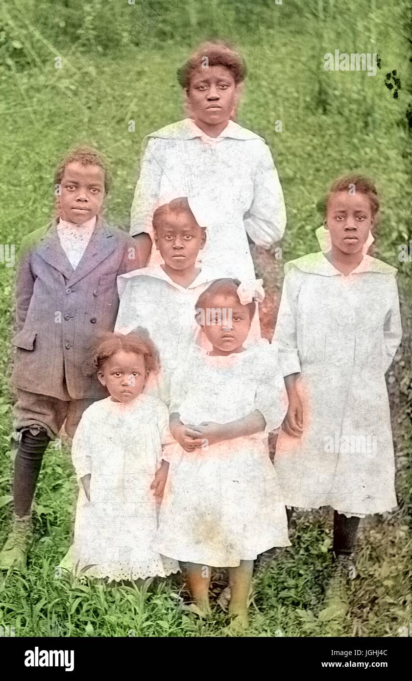 Porträt von einer afrikanischen amerikanischen Mutter und ihre fünf Kinder auf einem grasbewachsenen Hügel stehend, alle Mädchen sind in hellen Kleidern und der junge ist in einem dunklen Anzug, 1920. Hinweis: Bild wurde digital eingefärbt wurde mit einem modernen Verfahren. Farben können Zeit ungenau sein. Stockfoto
