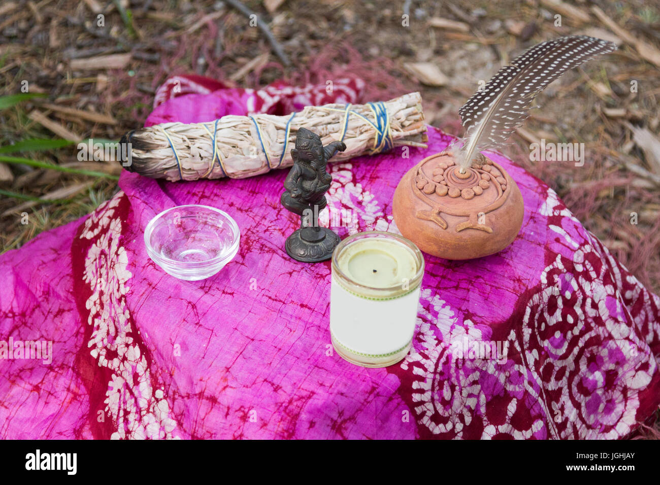 Altar mit Salbei, Wassernapf, Kerze, Töpferei Rattle, Feder- und Dancing ganesha auf dem Boden geschossen von oben Stockfoto