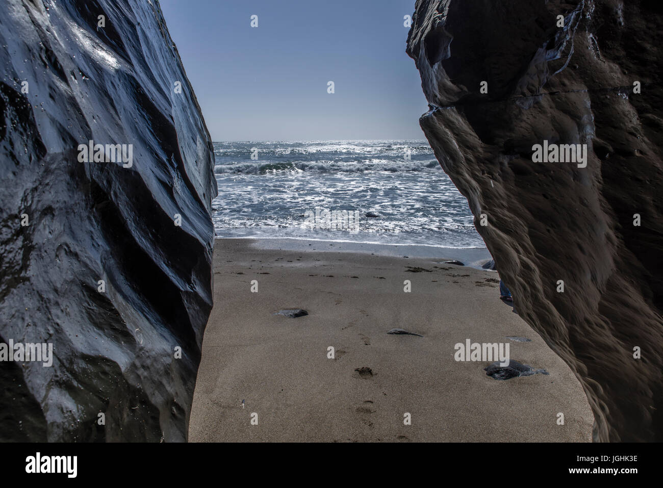 Surf und Wellen auf einer felsigen Küste mit grauen bewölktem Himmel Stockfoto