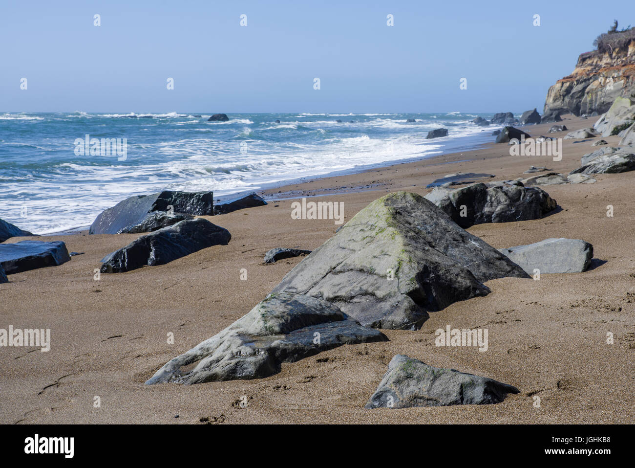 Surf und Wellen auf einer felsigen Küste mit grauen bewölktem Himmel Stockfoto