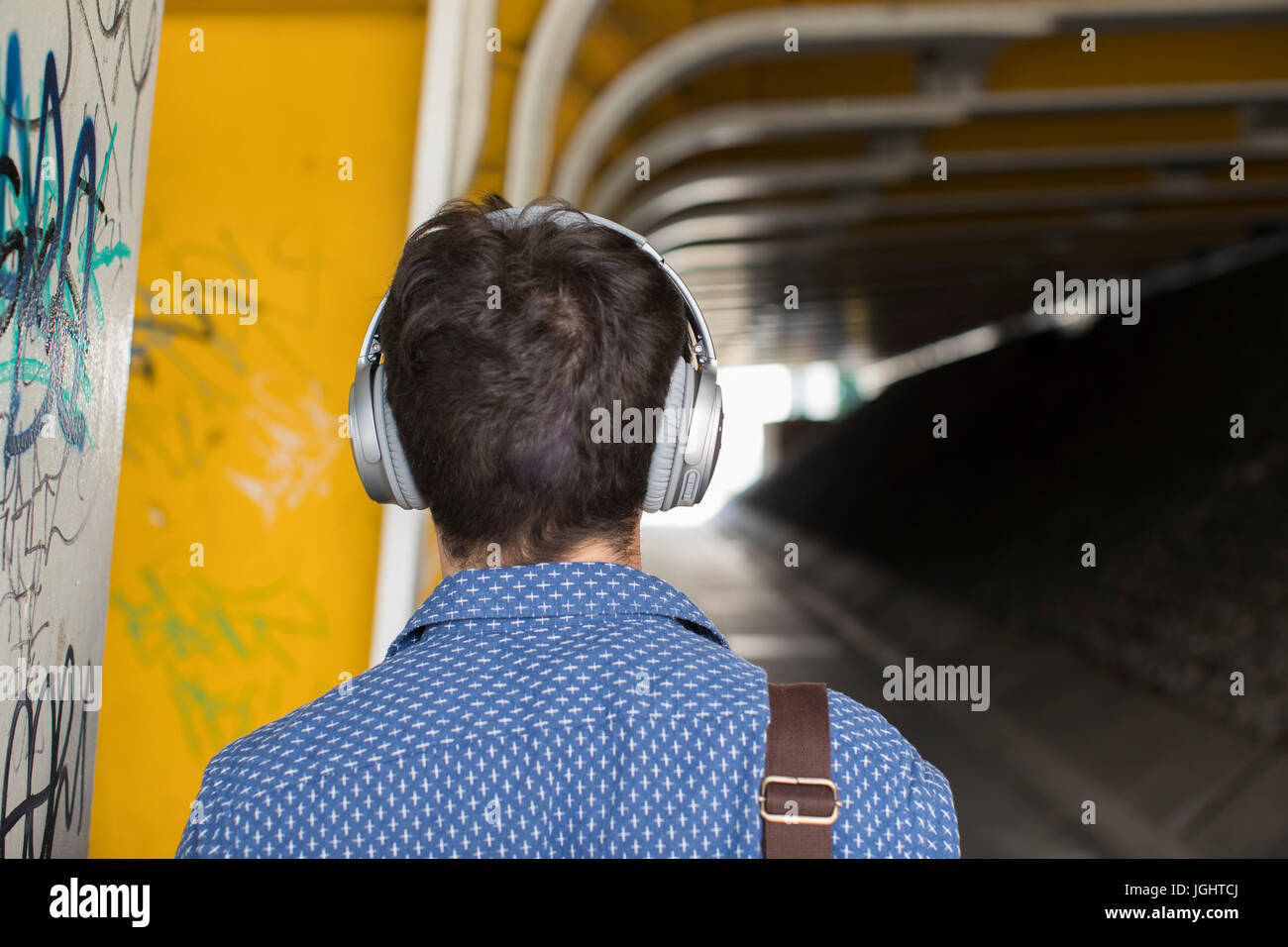 Rückansicht des Menschen im urbanen Umfeld mit Kopfhörern Stockfoto