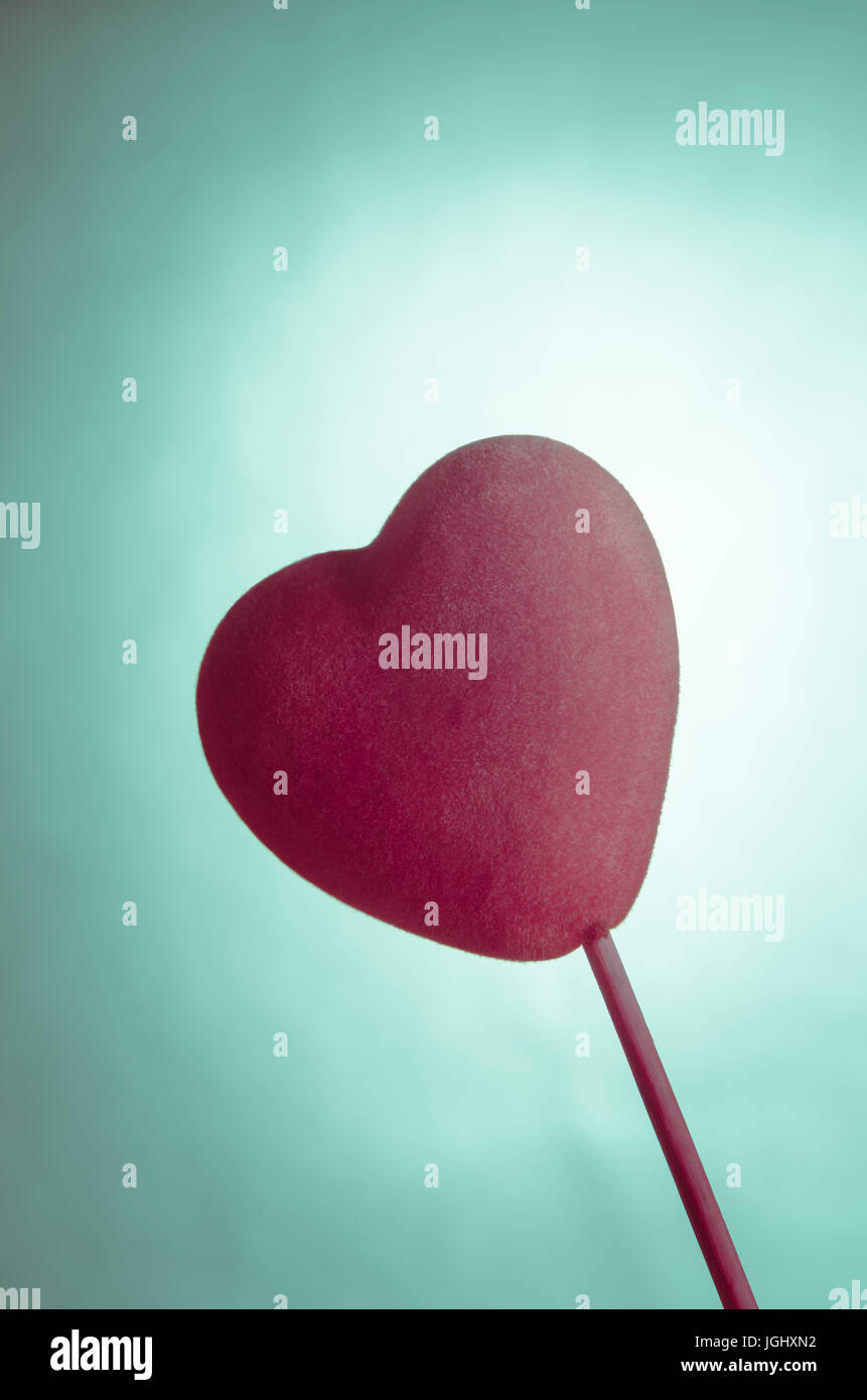 Weicher Stoff samtig rosa Herz auf einem Stick Türkis Hintergrund.  Kreuz verarbeitet für ein Retro-Gefühl "Jugendliebe". Stockfoto