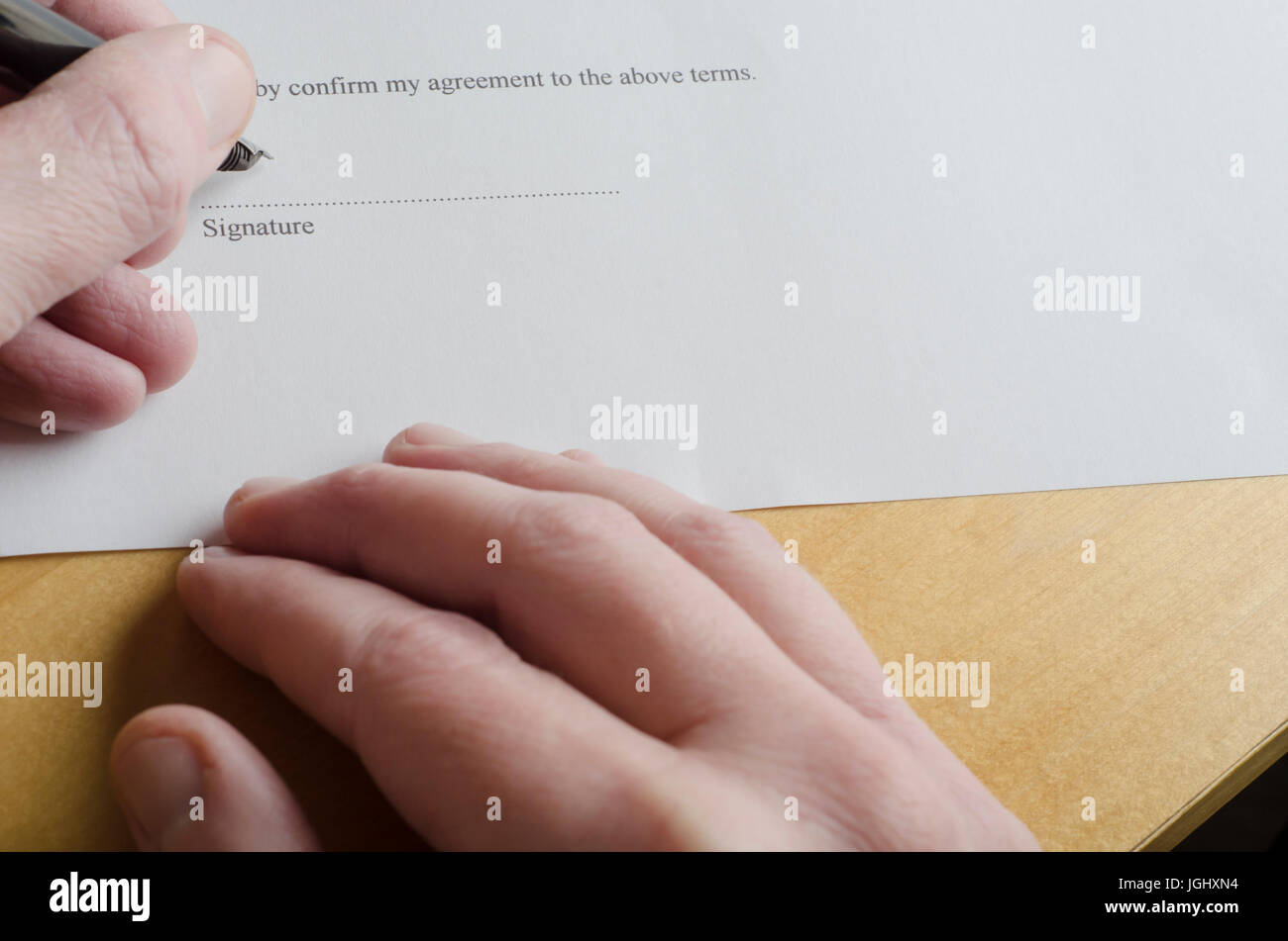 Nahaufnahme eines männlichen Hand Unterzeichnung "Signatur" Teil auf der gestrichelten Linie von einer weißen Urkunde mit Patrone Stiftspitze, während die andere Hand auf Licht ruht Stockfoto