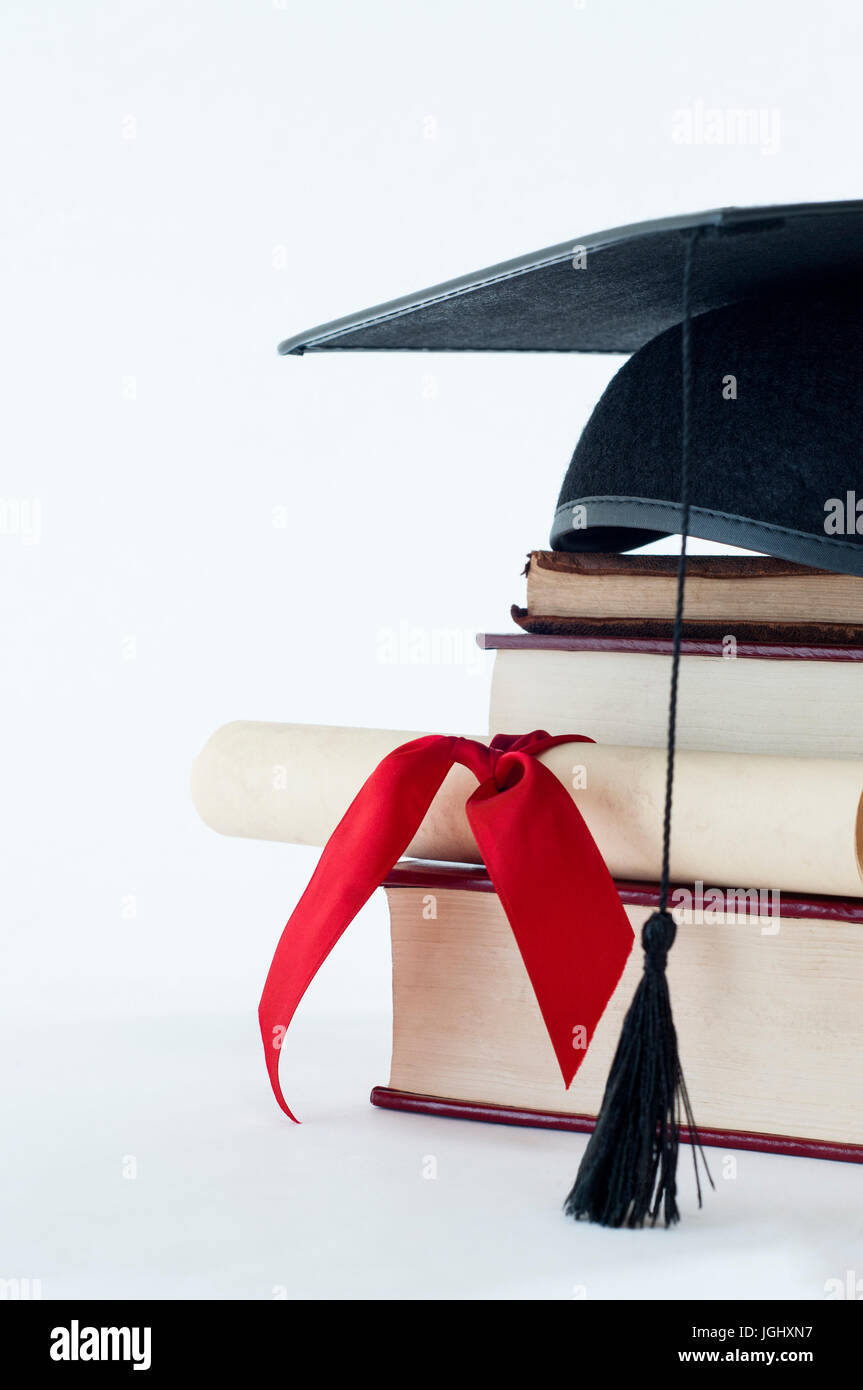Eine Graduierung Quaste auf einem Stapel Bücher, mit Pergament Schriftrolle in rot Ribvon gebunden. Stockfoto