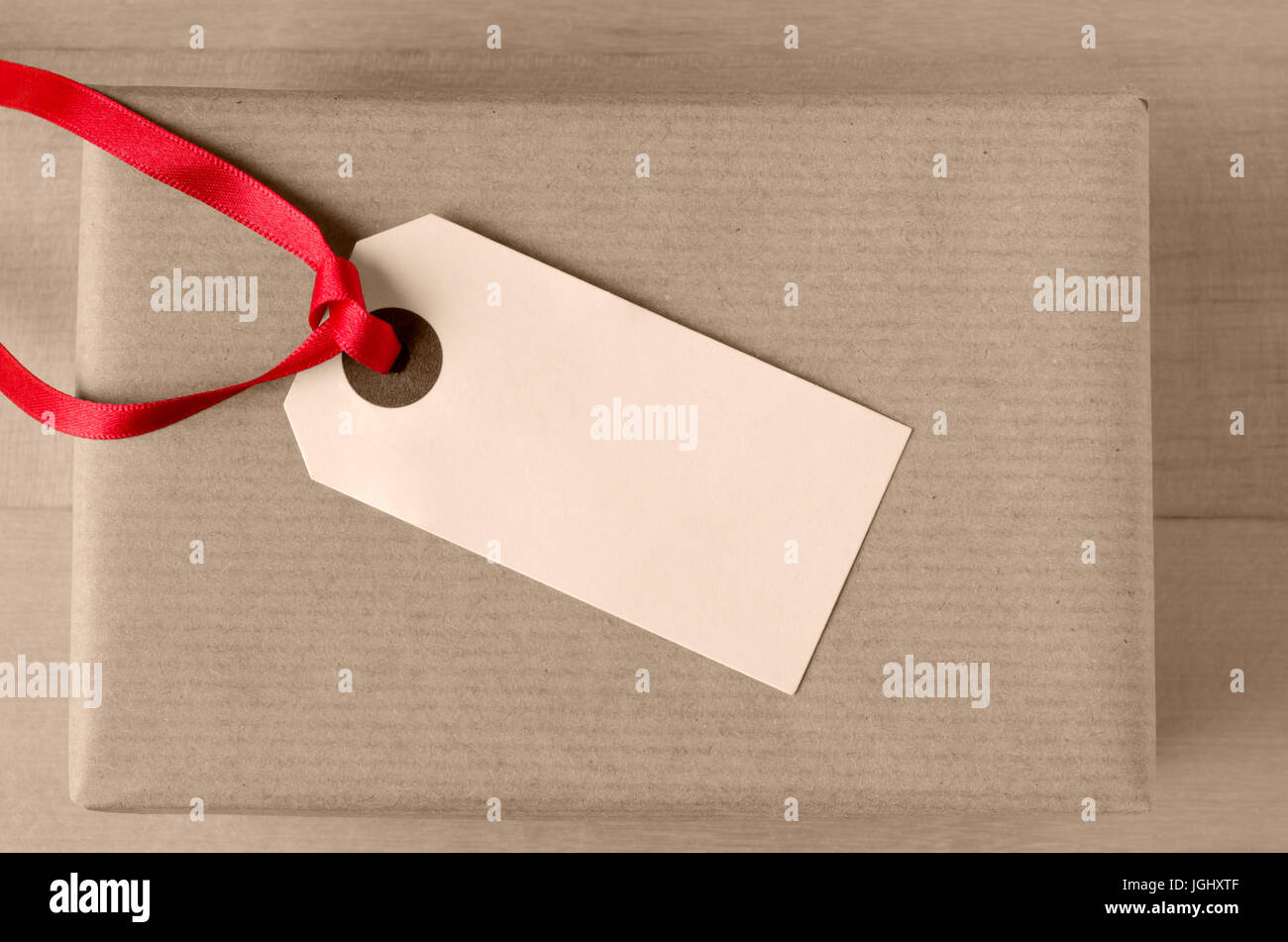 Overhead Schuss ein leeres Paket-Tag, mit roten Band gebunden und nach oben zeigt auf der Oberseite eine verpackte Packpapier-Geschenk-Paket. Stockfoto
