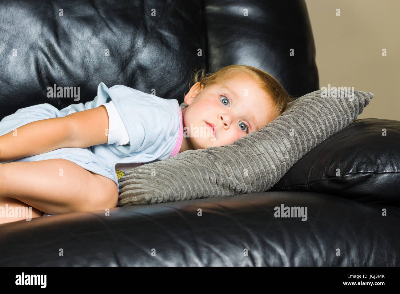 2 Jahre altes Mädchen im blauen Pyjama liegen auf der Couch Tagträumen Stockfoto