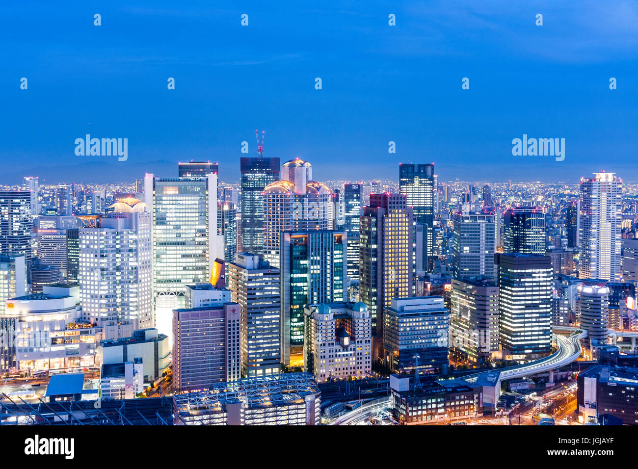 Stadt Osaka, Japan. Nacht Zeit hohen Betrachtungswinkel von der Oberseite der Umeda Sky Building. Hohes Bürogebäude mit Bergen im Hintergrund. Stockfoto