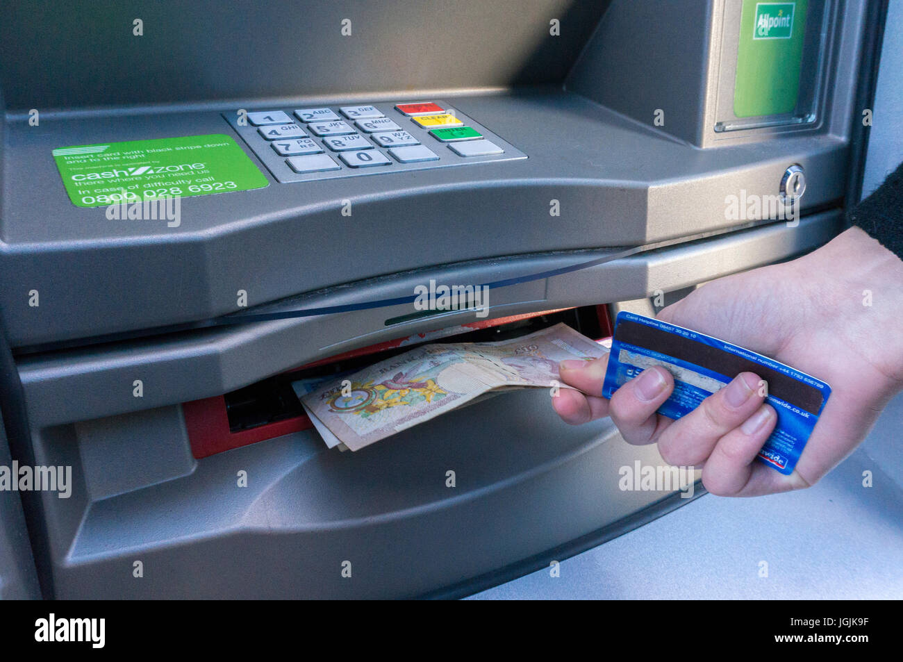 Eine Frau, die eine Kredit- oder Debitkarte unter zehn Pfund Sterling Anmerkungen von einem Geldautomaten Geldautomaten. London, England, UK. Stockfoto