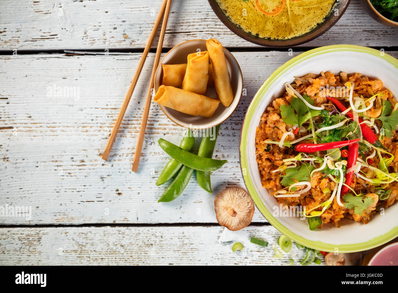Asiatischen Huhn und Garnelen curry mit Reis und Frühlingsrollen Stücke, Ansicht von oben auf alten Holzdielen serviert. Stockfoto