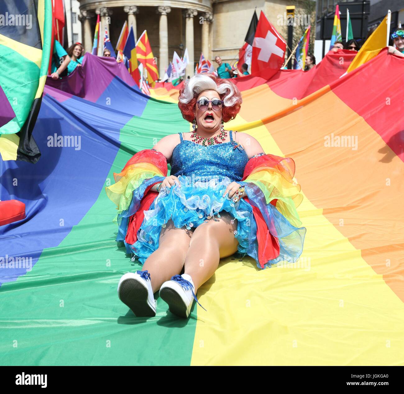 Ein Teilnehmer sitzt auf einem Regenbogen farbige Flagge während der Pride in London Parade im Zentrum von London. Stockfoto