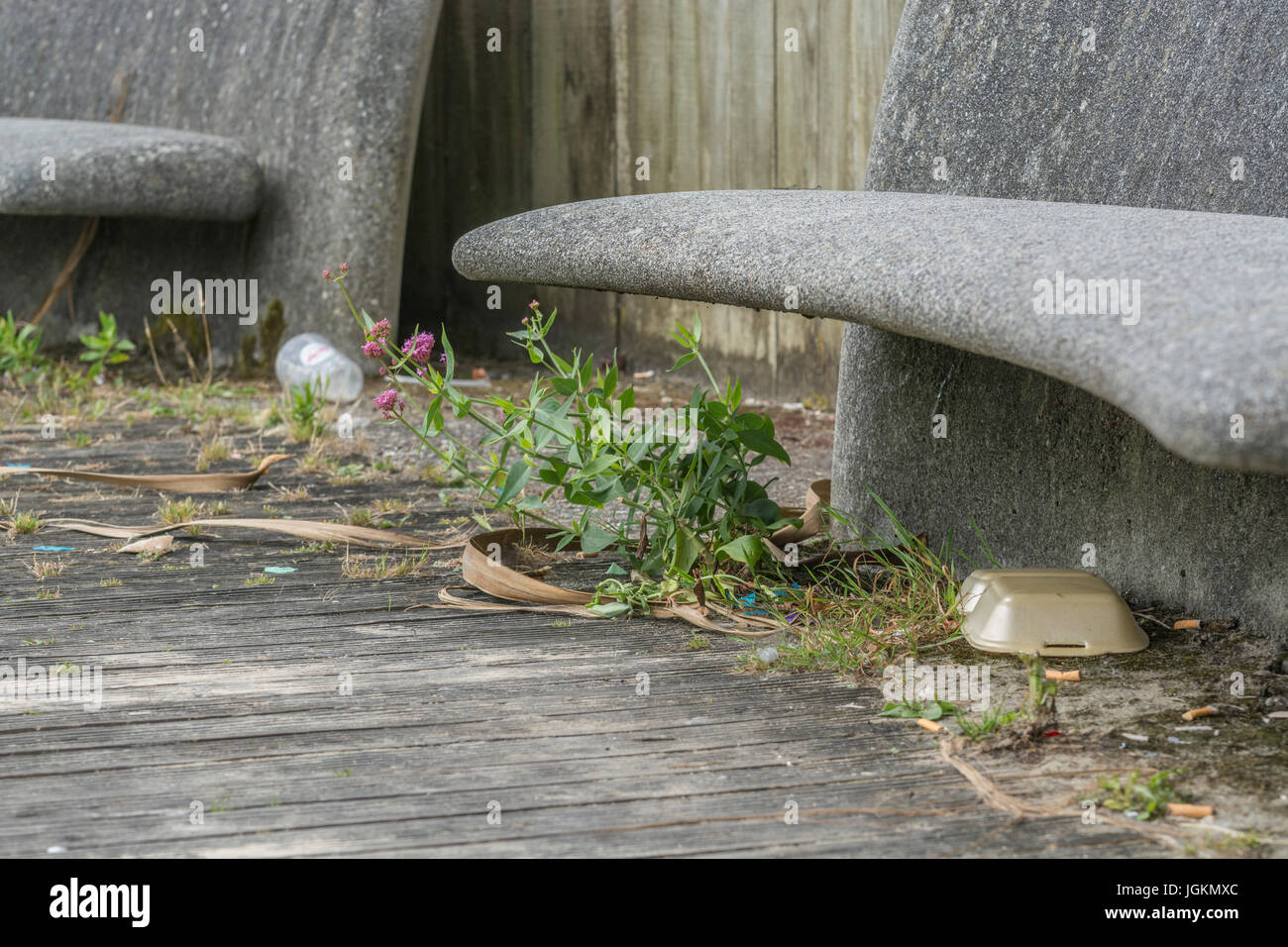 Urban Wurf, Kunststoff takeaway Abfälle, und konkrete öffentliche Sitzgelegenheiten in der Cornish Badeort von Newquay. Metapher Krieg auf Kunststoff, plastik Müll. Stockfoto