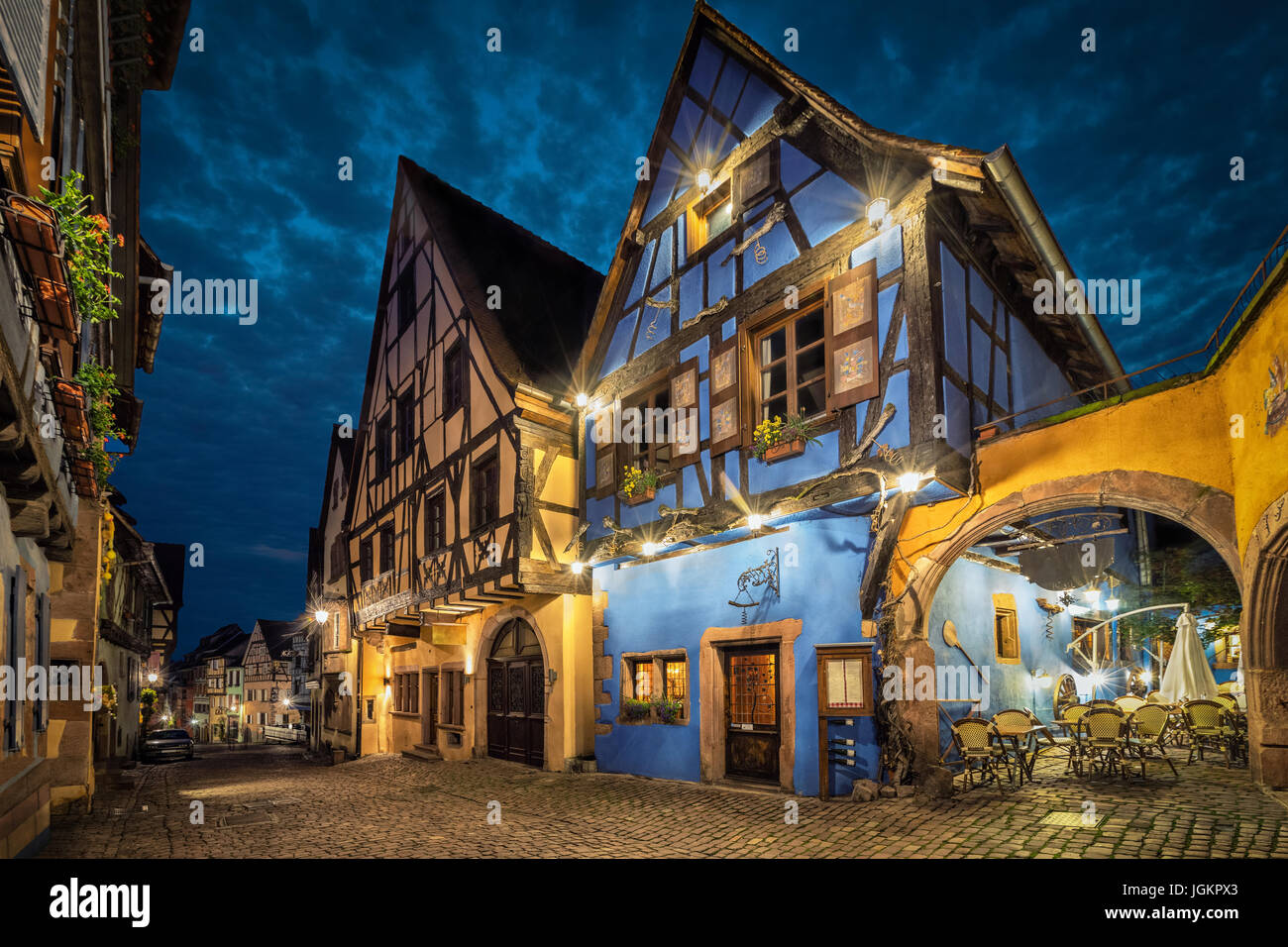 Bunte traditionelle französische Fachwerkhäuser auf der zentralen Straße von Riquewihr Dorf am Abend, Elsass, Frankreich Stockfoto