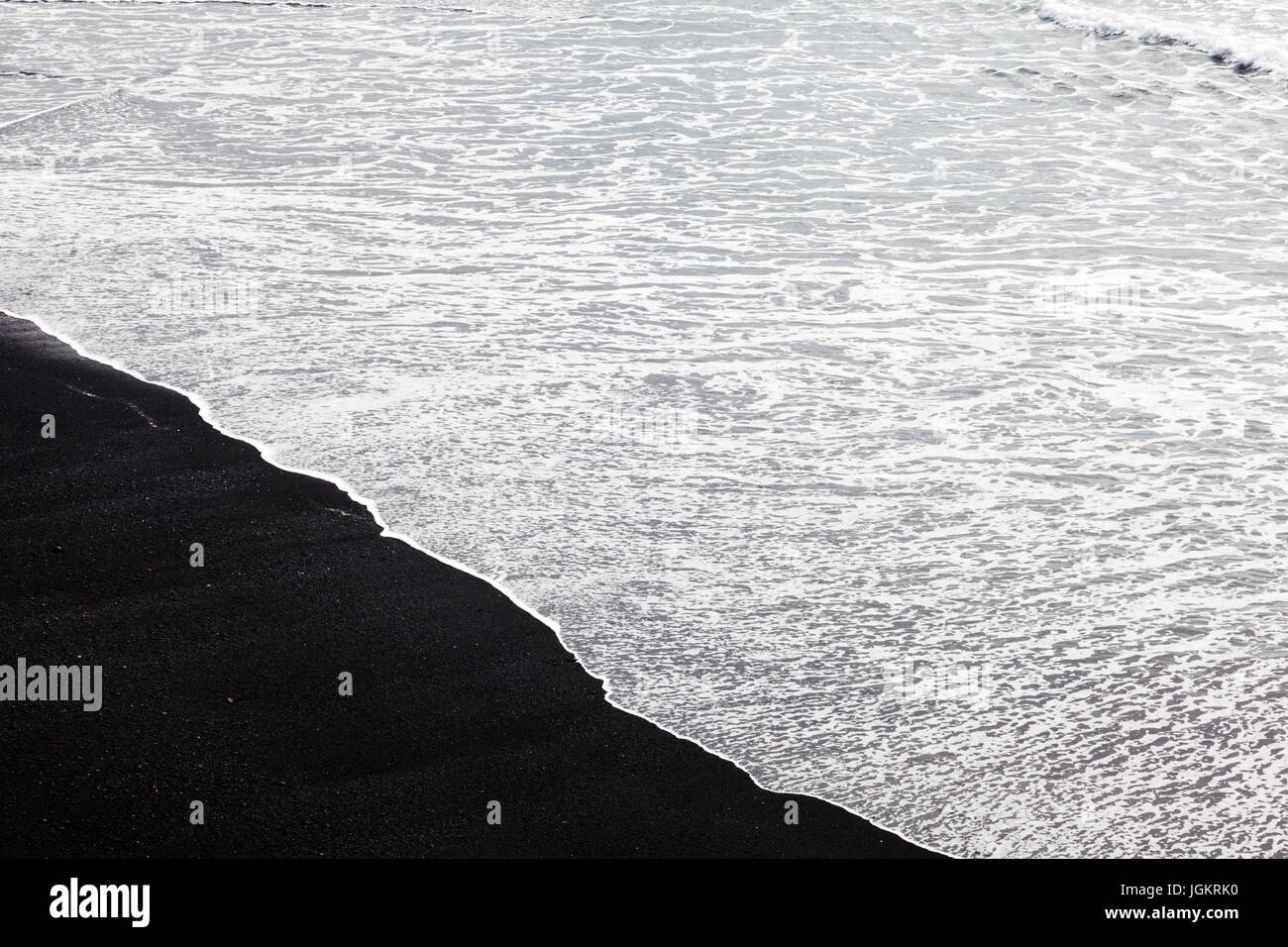 Weiße Welle Schaum abwaschen auf einem schwarzen Sandstrand in Island Stockfoto
