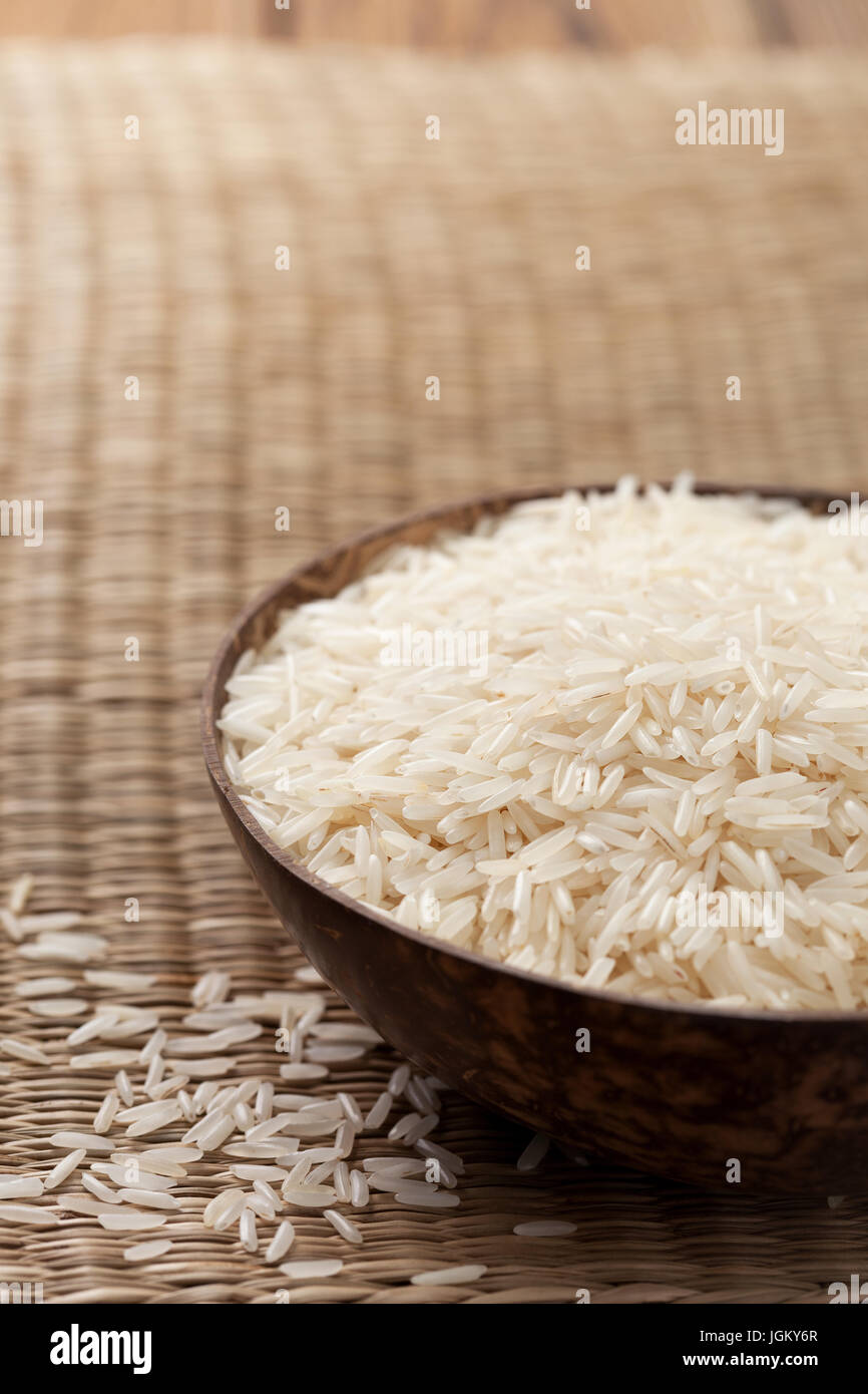 Basmati-Reis in Holzschale auf Stroh Hintergrund Stockfoto