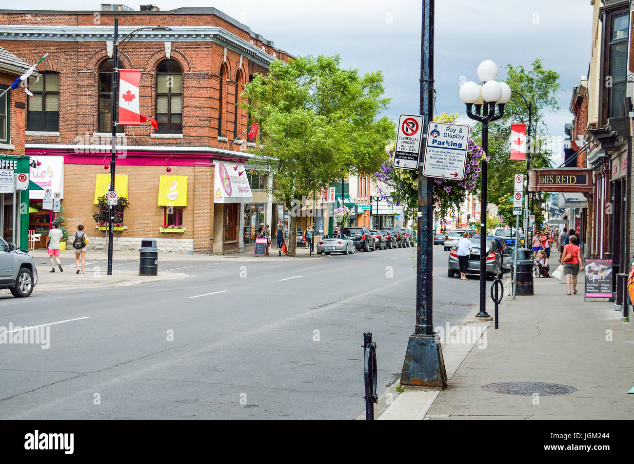 Kingston, Kanada - 23. Juli 2014: Downtown City im Sommer mit kanadischen Flaggen und Menschen zu Fuß auf der Hauptstraße Stockfoto