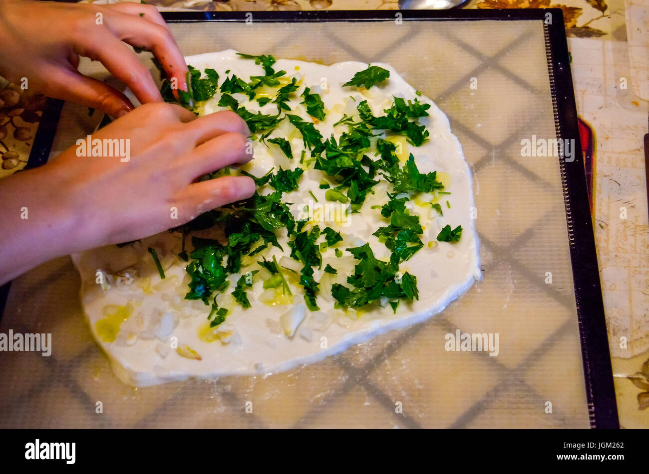Junge Frau Hände Brotbacken im Dörrgerät mit Zwiebel, Petersilie und weiße Kokosnuss Fleisch Teig Stockfoto