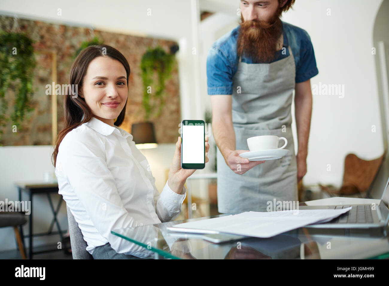 Junge Geschäftsfrau Datenaustausch im Smartphone mit Kellner in der Nähe von Stockfoto