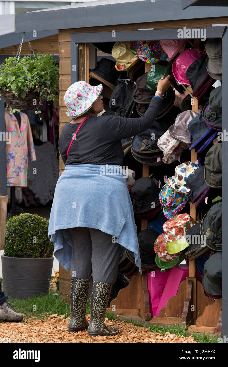 1 Frau Kunde Blick auf Lager & anprobieren Hut vom Handel Stall Display - RHS Chatsworth Flower Show, Chatsworth House, Derbyshire, England, UK. Stockfoto