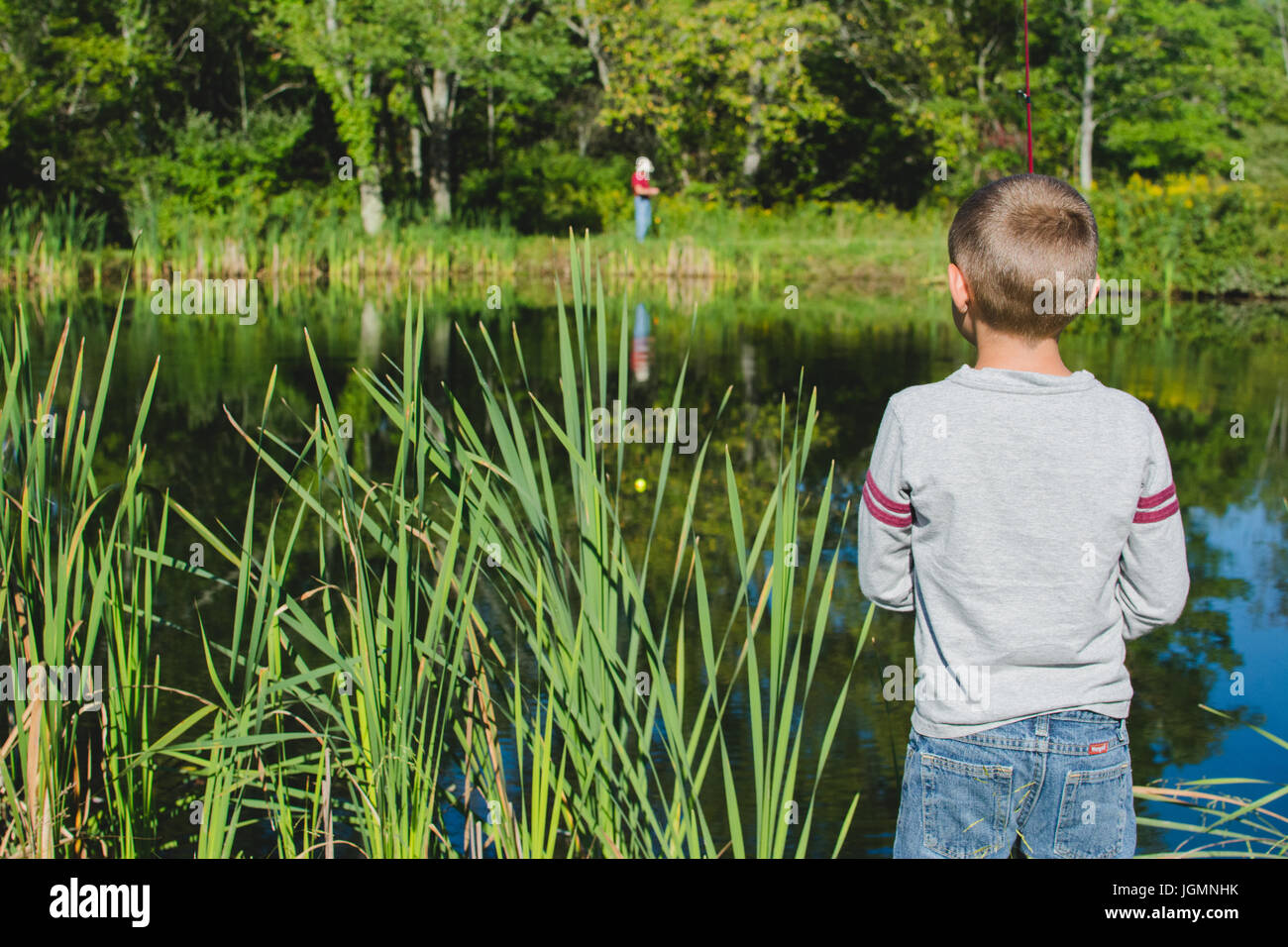 Ein Kind, Angeln an einem Dock an einem Teich in einer ländlichen Gegend. Stockfoto