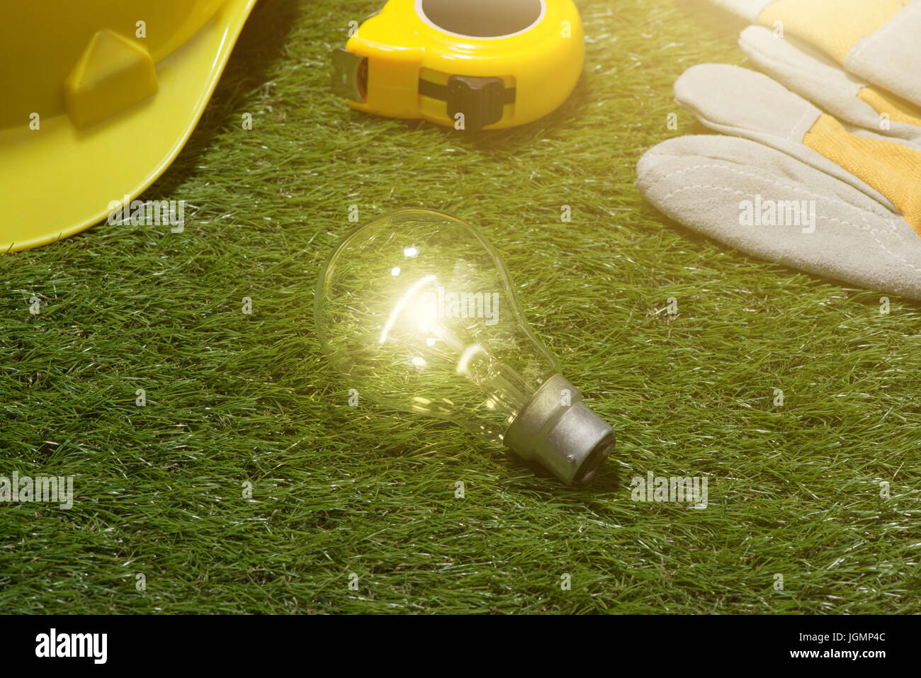 Haus Ingenieur und Architekt Ideen Konzept mit Glühbirne. Yellow hat und Tools auf grünem Gras Hintergrund Stockfoto