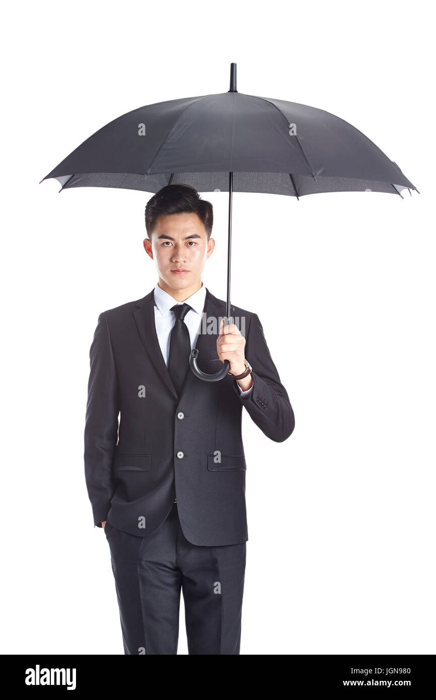 junge asiatische Geschäftsmann in Abendgarderobe hält einen Blick in die Kamera mit einer Hand in der Tasche, Schirm isoliert auf weißem Hintergrund. Stockfoto