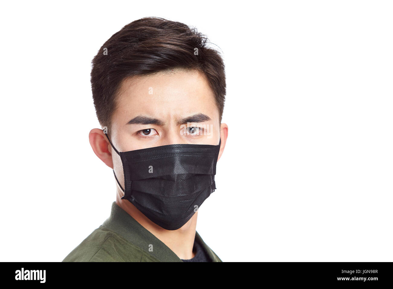 junge asiatische Mann mit schwarzer Maske starrte in die Kamera, isoliert auf weißem Hintergrund. Stockfoto