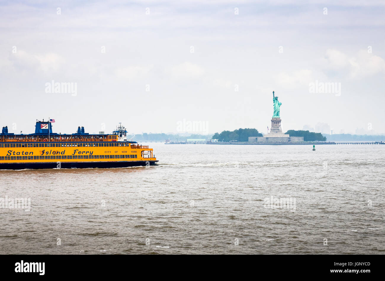 Eine Fähre nach Staten Island gleitet vor der Statue of Liberty, New York Harbor, New York City, Vereinigte Staaten von Amerika. Stockfoto