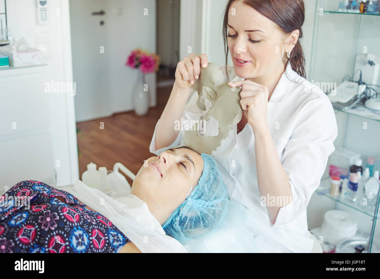 Kosmetikerin, die Maske vom Gesicht des Patienten entfernen. Stockfoto