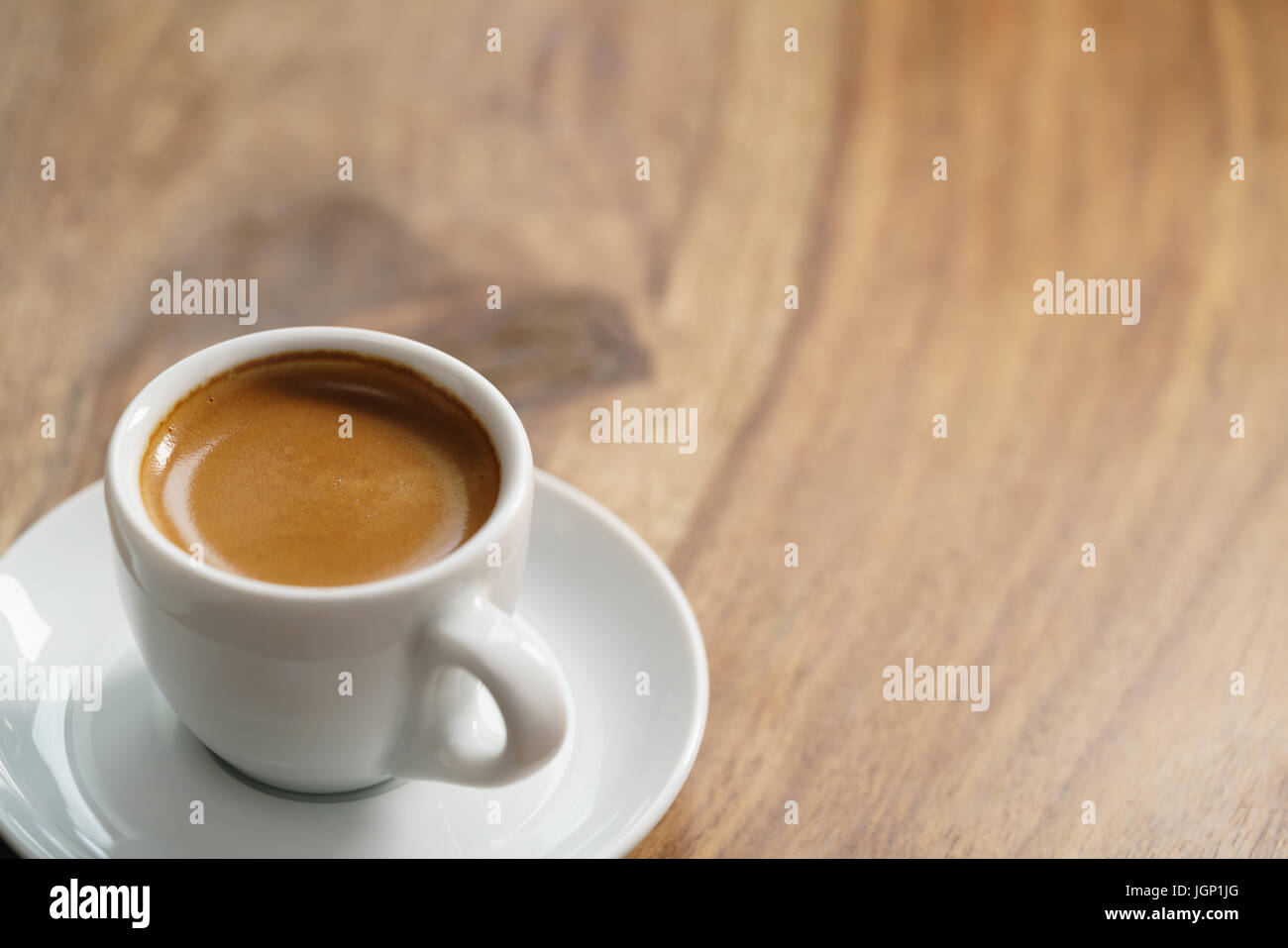 Schneiden Sie frischer Espresso in weiß auf Holztisch Stockfoto