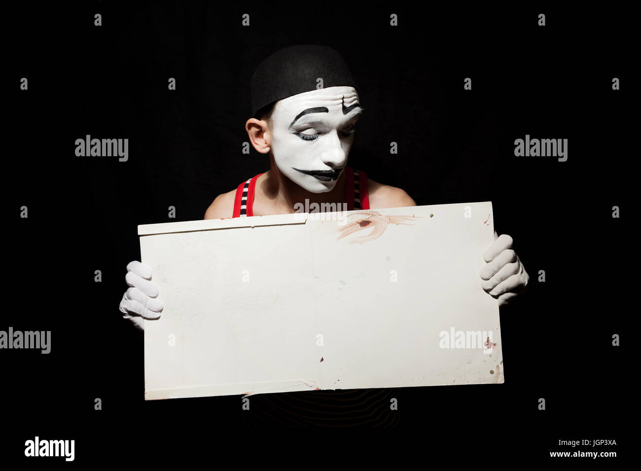 Porträt von traurig Mime schmutzig Blatt weißes Papier in den Händen halten.  Studio Foto auf einem schwarzen Hintergrund Stockfoto
