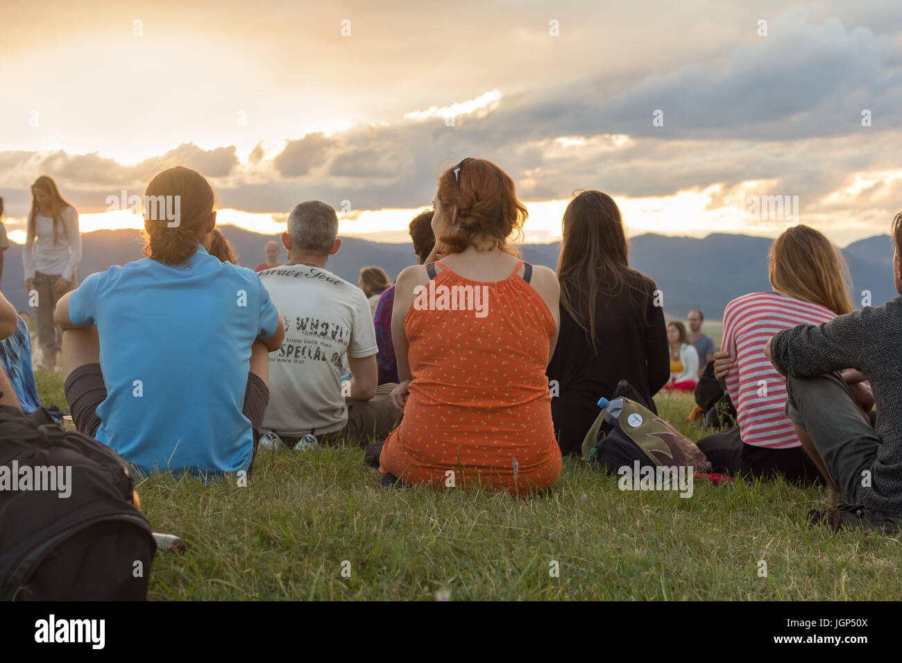 Gruppe von Menschen auf dem Rasen sitzen und genießen Sie spektakuläre Sonnenuntergang Stockfoto