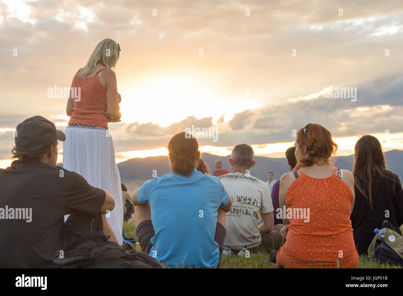 Gruppe von Menschen auf dem Rasen sitzen und genießen Sie spektakuläre Sonnenuntergang Stockfoto