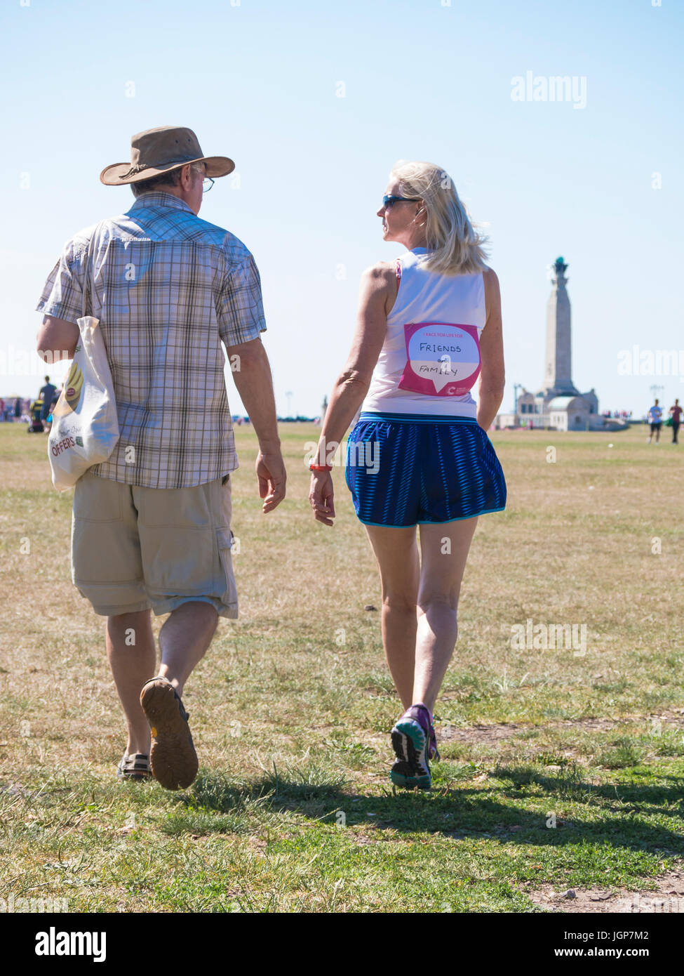 Ein Mann und eine Frau gehen über ein Feld mit der Dame im laufenden Kleidung und ein Rennen für das Leben"-T-Shirt Stockfoto