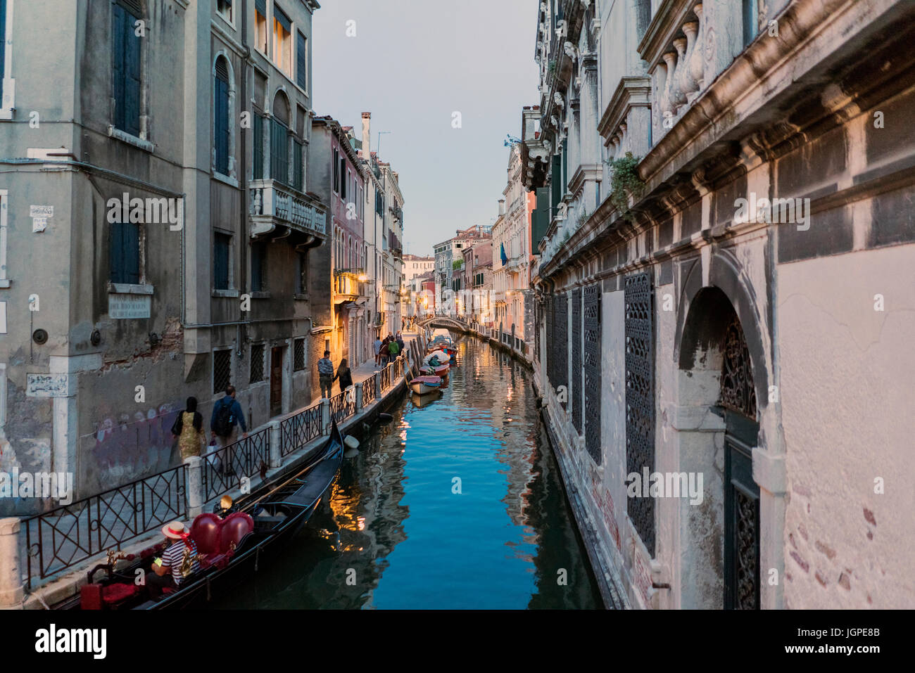 Kanal namens "Rio Marin" und Verankerung namens "Garzotti" in der Abenddämmerung mit Passanten und Gondeln in Venedig, Italien Stockfoto