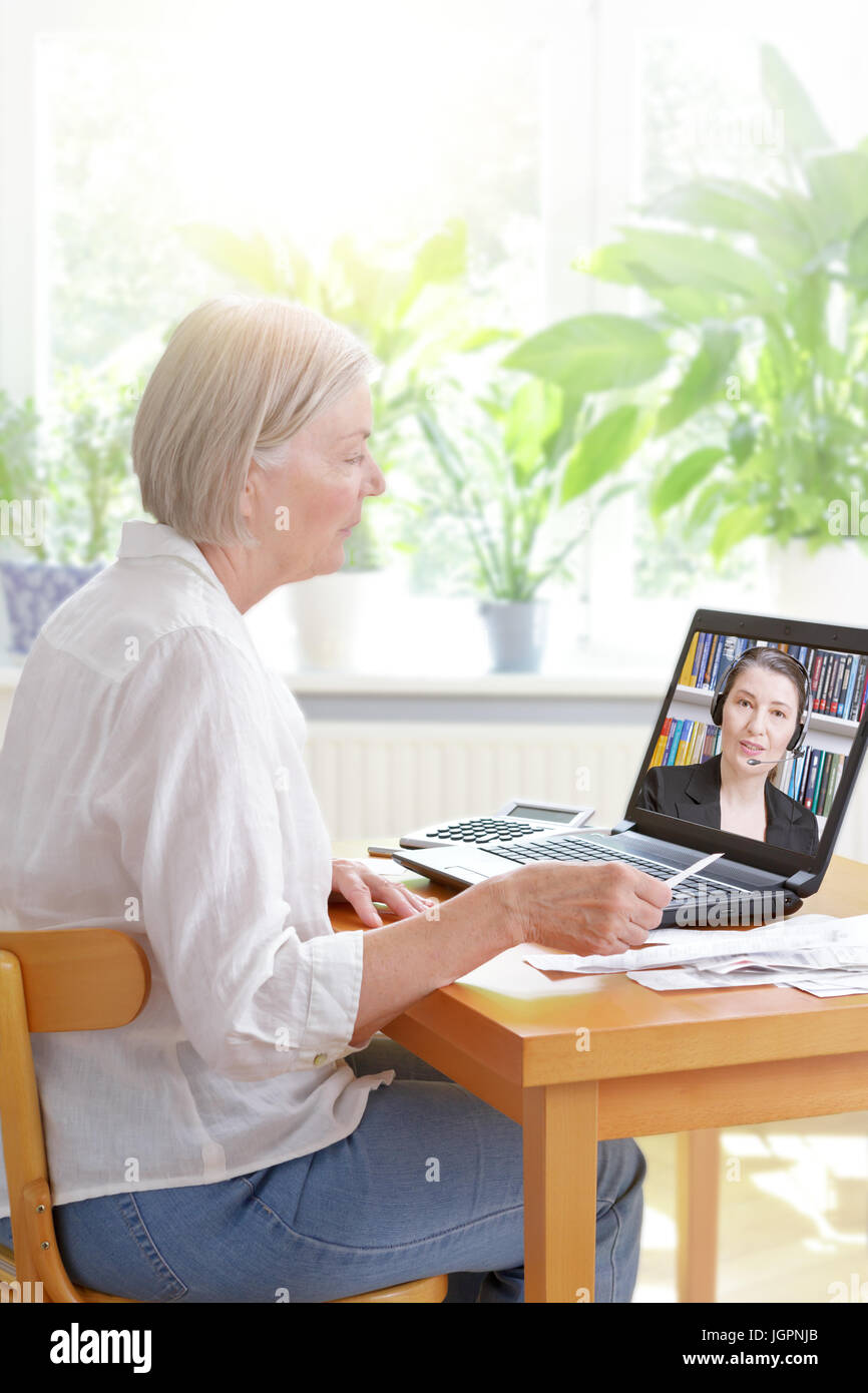 Ältere Frau zu Hause mit Ihrem Laptop und viele Einnahmen, Zuhören, ein Buchhalter, bevor Sie Ihre jährliche Steuererklärung, online Steuerberatung conc Stockfoto